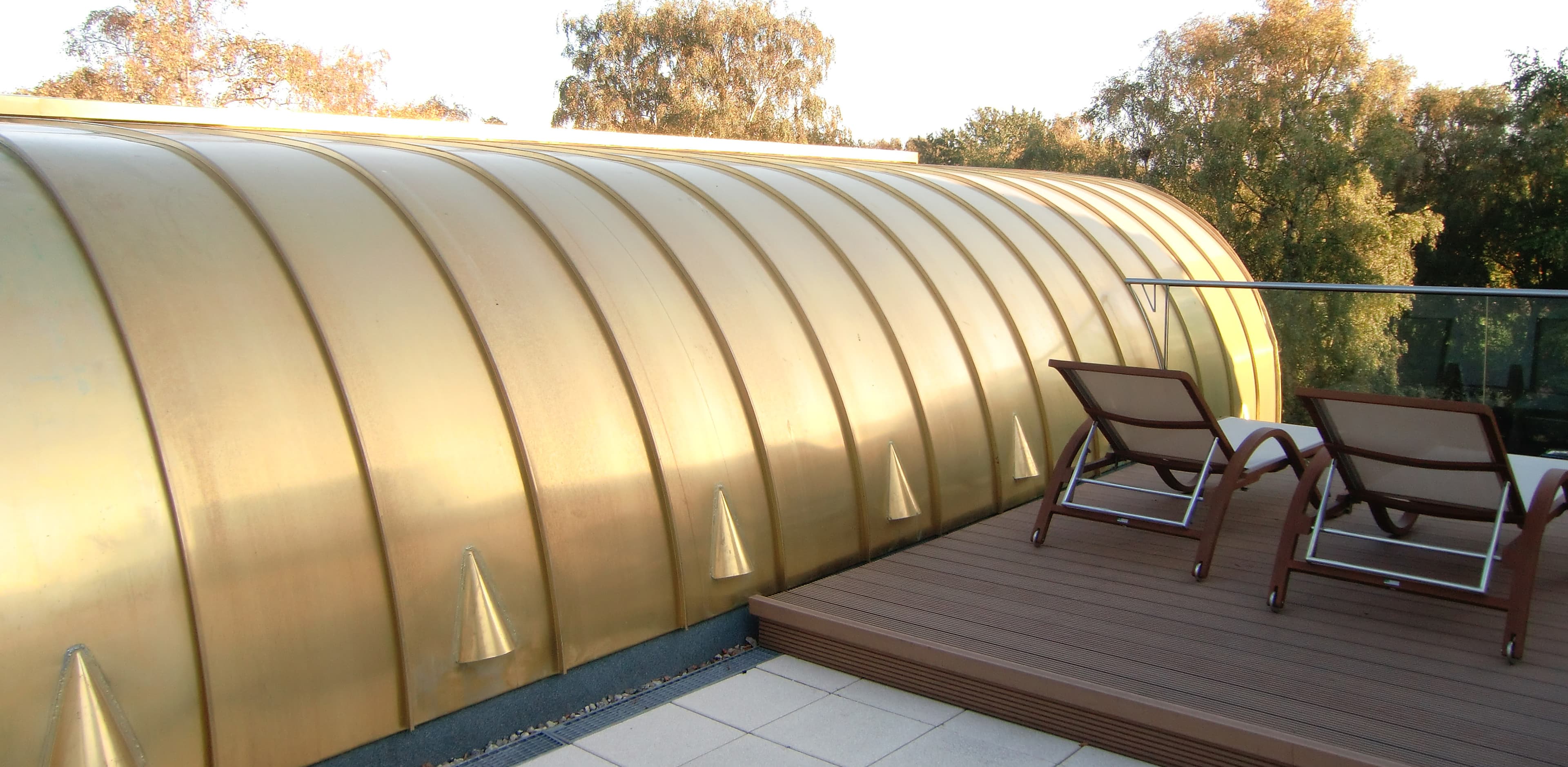 Terrasse mit zwei Liegen neben einem gewölbten Metalldach