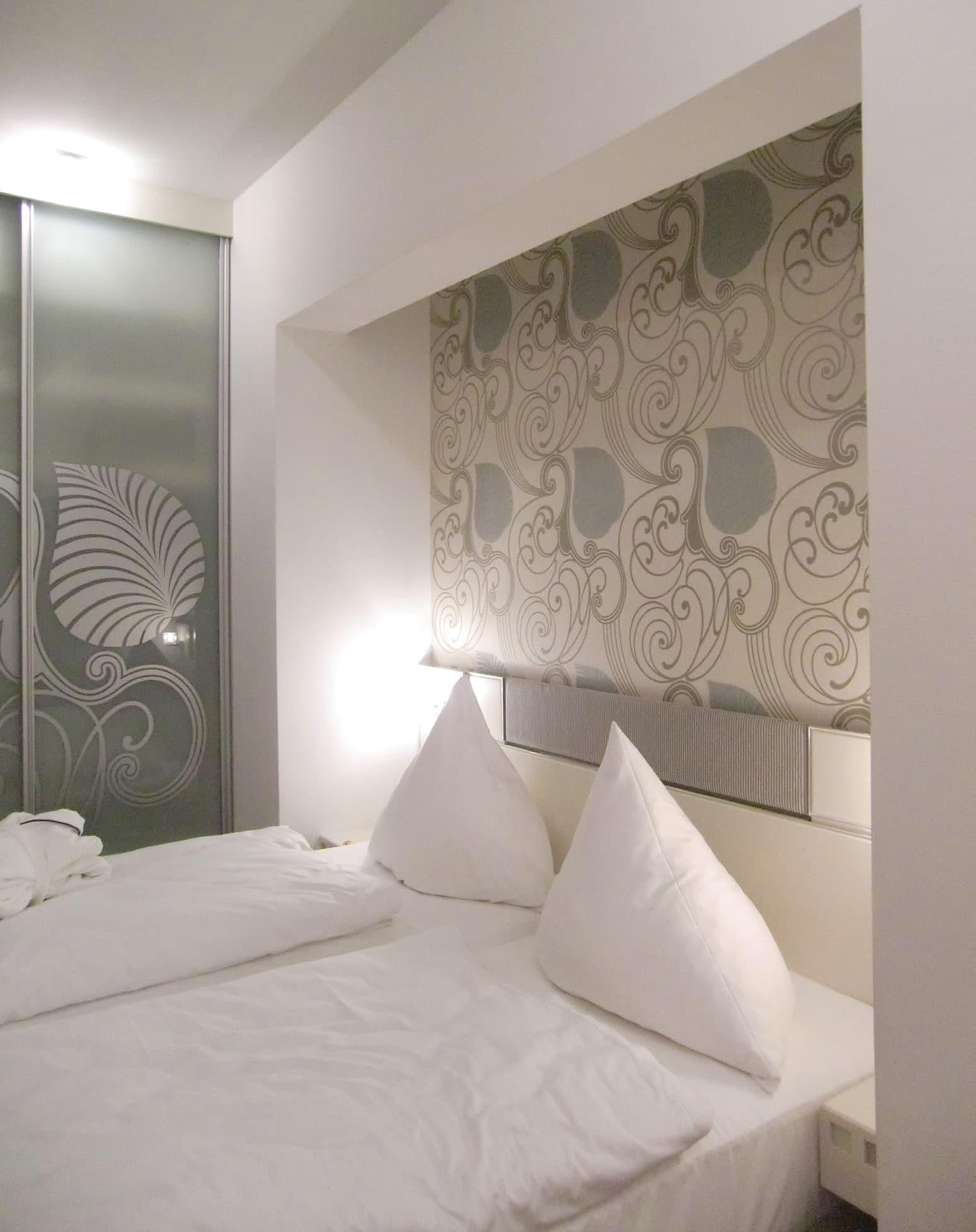 Doppelbett vor gemusterter Tapete in einer Nische