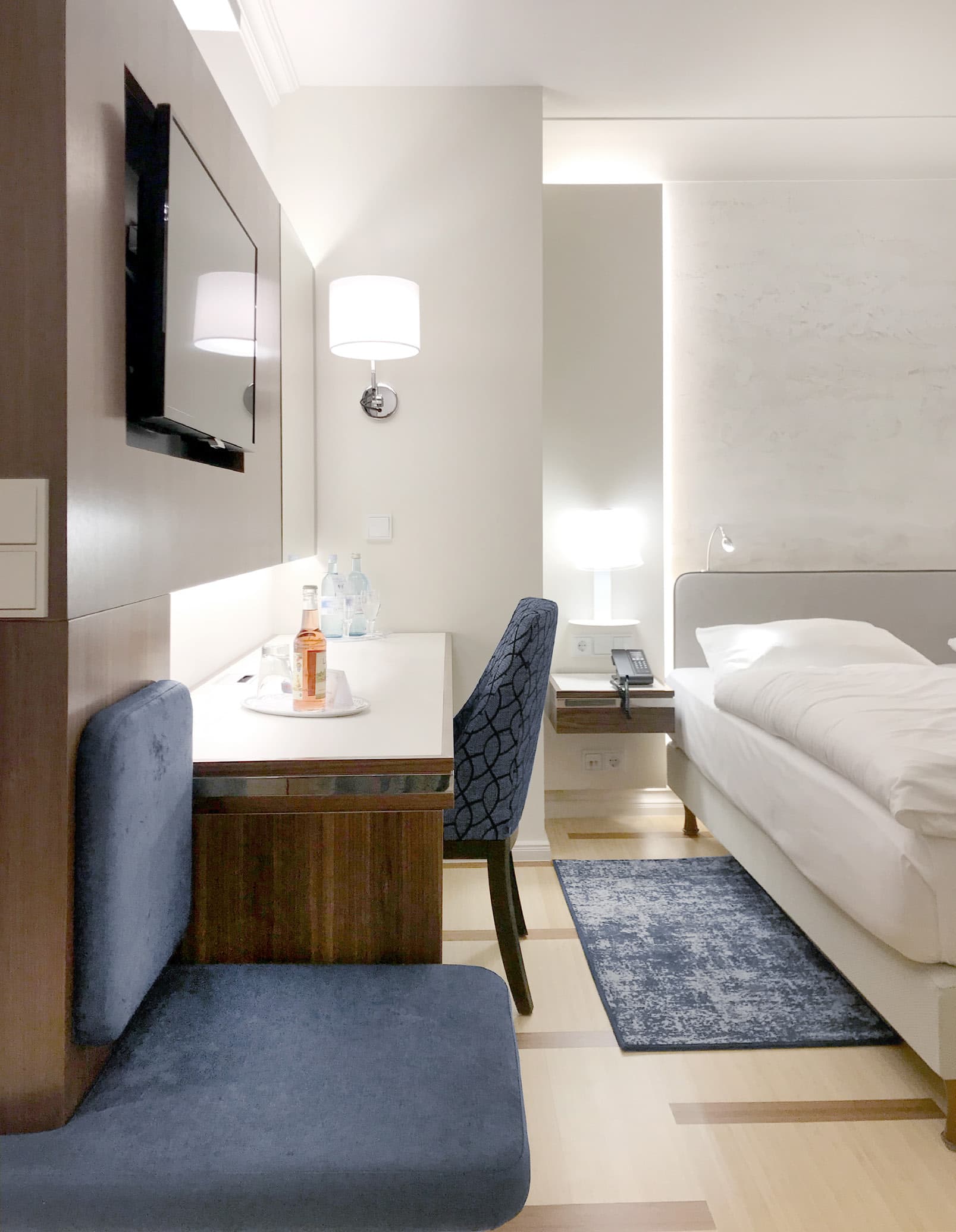 Hotelzimmer mit Schreibtisch, Polsterbank und Bett