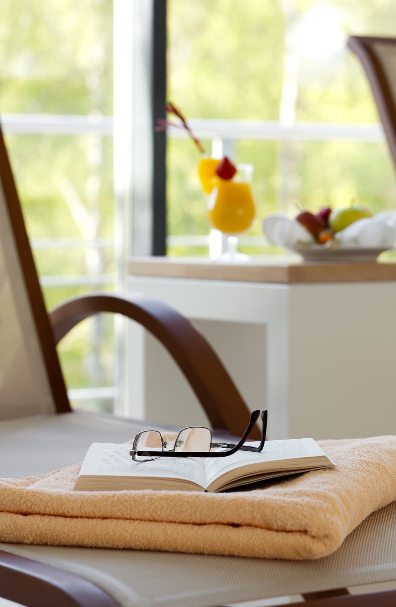 Aufgeschlagenes Buch mit Brille auf einem Handtuch, dahinter ein Fenster