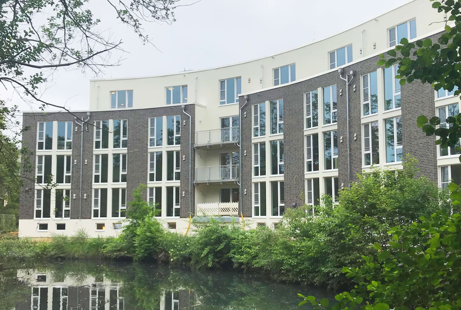 Mehrgeschossiges Wohngebäude mit Klinkerfassade an einem Wasserlauf
