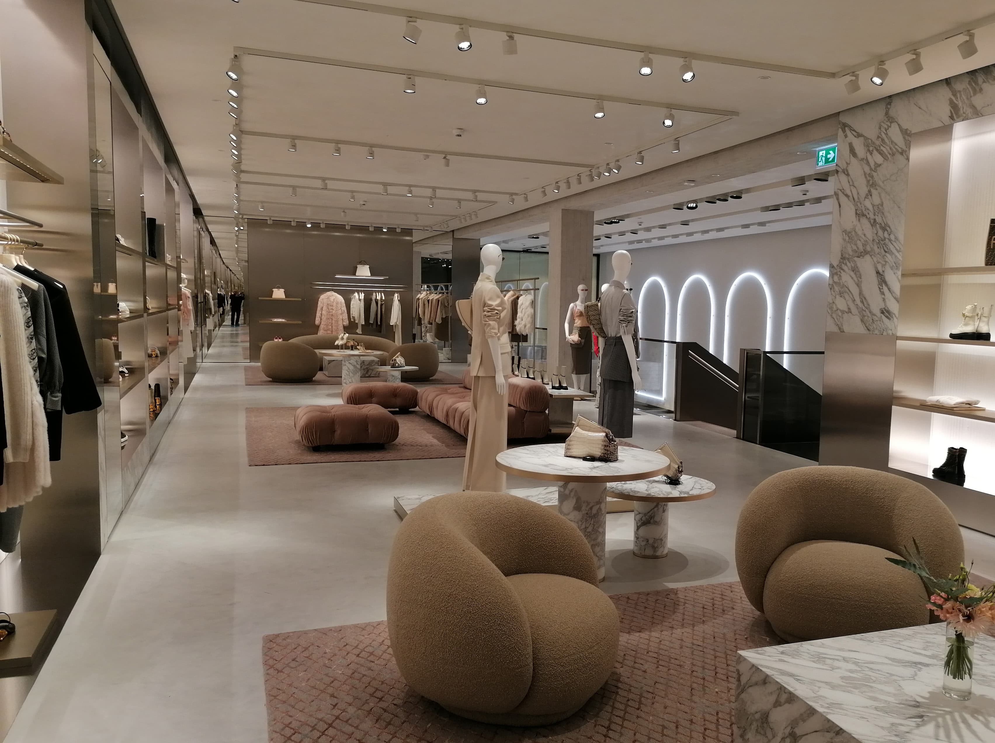 Verkaufsraum mit Polstersesseln, Regalen und beleuchteten Bögen an der Wand